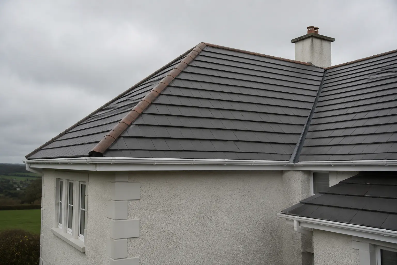A newly completed tiled roof with hipped ends and a rendered chimney